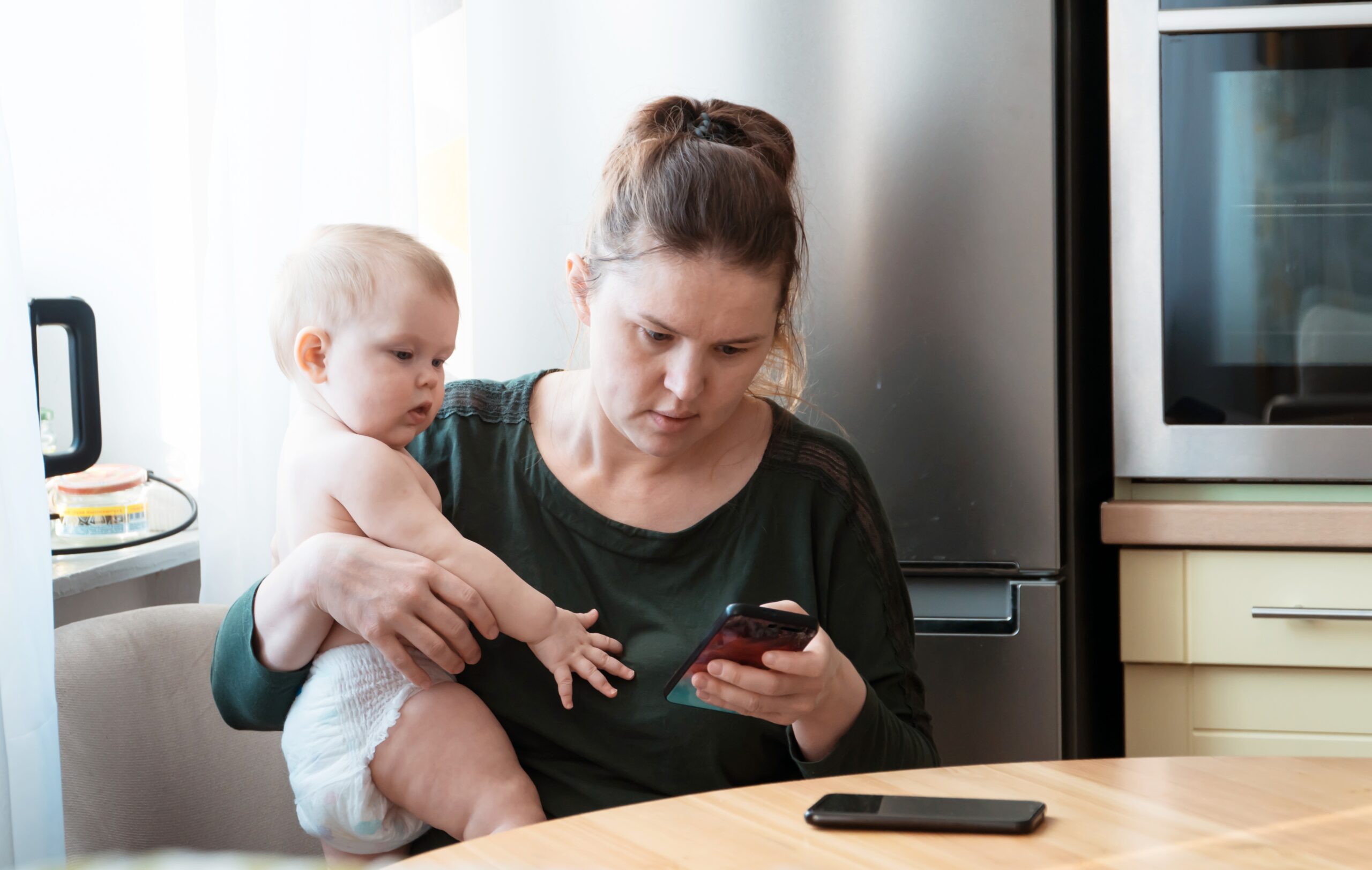 mom scrolling through phone with baby